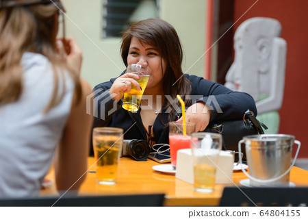 Happy young Asian women as friends hanging out and drinking beer outdoors Happy young Asian women as friends hanging out and drinking beer outdoors 64804155