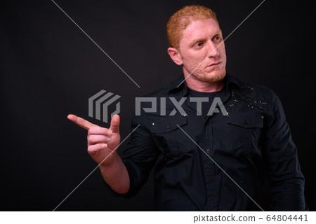 Portrait of muscular man with orange hair pointing finger Portrait of muscular man with orange hair pointing finger 64804441