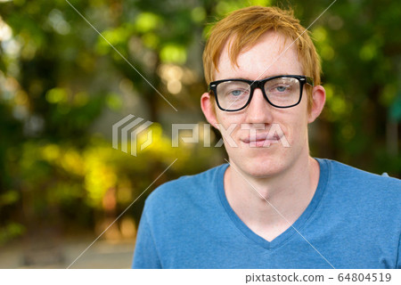 Face of nerd man with red hair wearing eyeglasses in the park 64804519