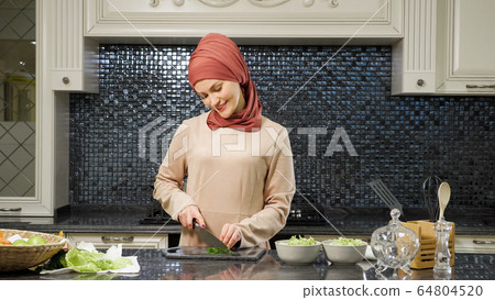 oriental woman cooks meal cutting fresh greens smiling oriental woman cooks meal cutting fresh greens smiling 64804520