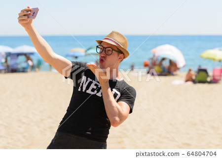 Young nerd tourist man taking selfie at the beach Young nerd tourist man taking selfie at the beach 64804704