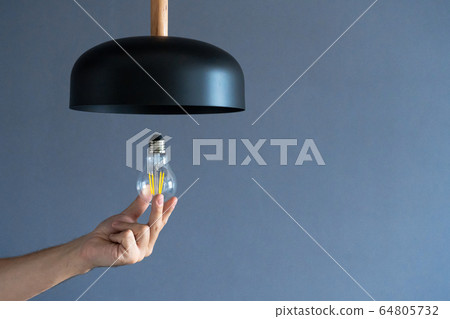 Close-up. A hand changes a light bulb in a stylish Close-up. A hand changes a light bulb in a stylish 64805732