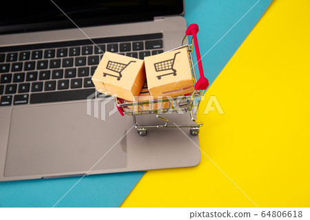 Three paper boxes in a small shopping cart on a laptop keyboard. Online shopping and delievery concept 64806618