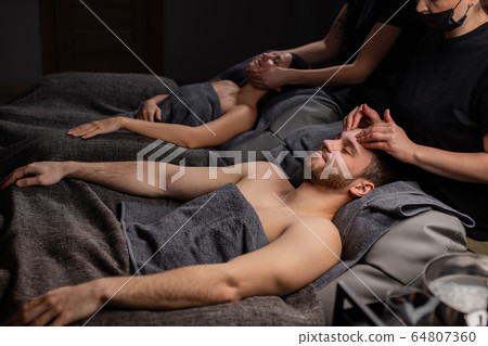 happy couple lying on massage desks in spa salon happy couple lying on massage desks in spa salon 64807360