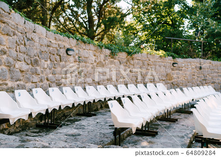 White plastic chairs in the amphitheatre in the old town of Bar, in Montenegro. 64809284