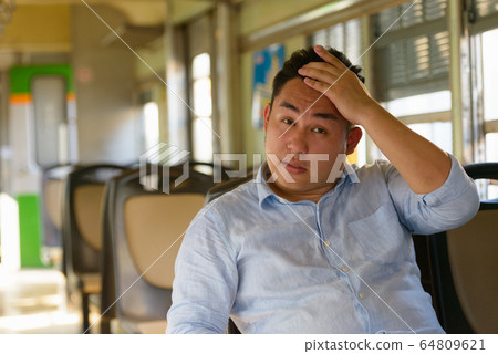 Stressed overweight Asian tourist man feeling hot inside the train Stressed overweight Asian tourist man feeling hot inside the train 64809621