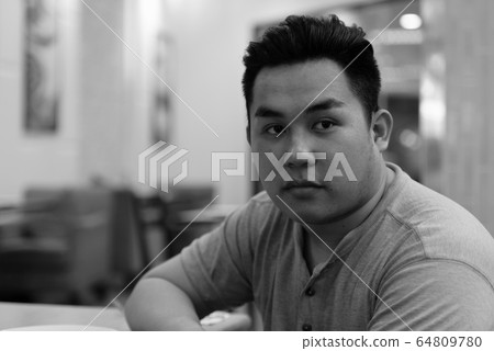 Face of young overweight Asian man thinking at the coffee shop 64809780