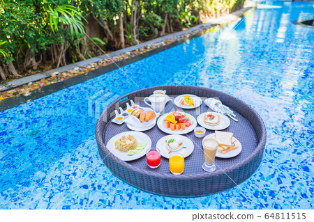 Floating breakfast set in tray with fried egg omelette sausage ham bread fruit milk juice coffee 64811515