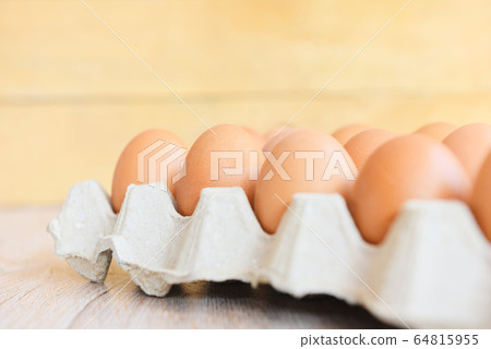 Eggs in egg box on wooden background / Close up of 64815955