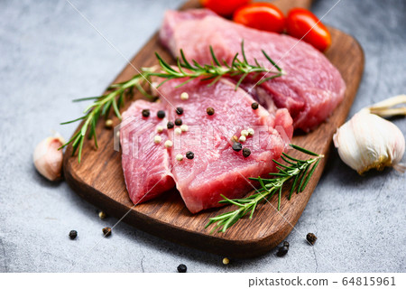 Raw pork meat on wooden cutting board at kitchen 64815961