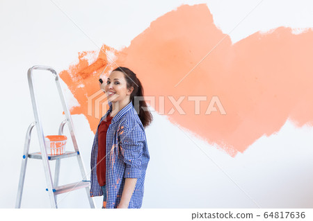 Cheerful woman painting the walls of new home. Renovation, repair and redecoration concept. Copy space. 64817636