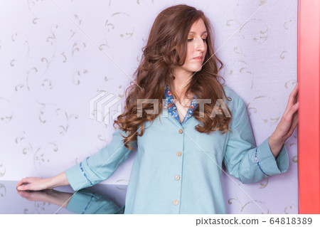 Young attractive woman dressed in beautiful colorful pajama posing as a model in her bedroom. Comfortable sleepwear, home relaxation and female fashion concept. Young attractive woman dressed in beautiful colorful pajama posing as a model in her bedroom. Comfortable sleepwear, home relaxation and female fashion concept. 64818389