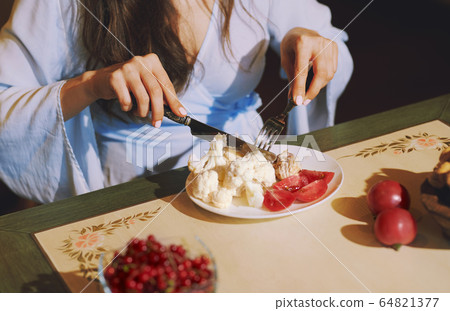 Vegetarian woman sitting at the table and eating Vegetarian woman sitting at the table and eating 64821377