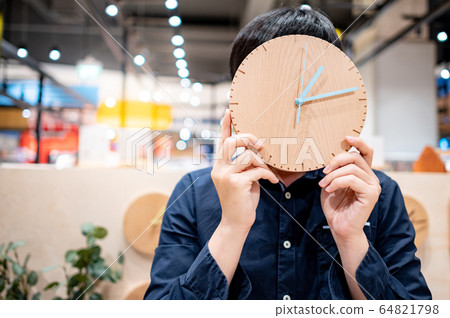 Asian man holding clock hiding his face Asian man holding clock hiding his face 64821798