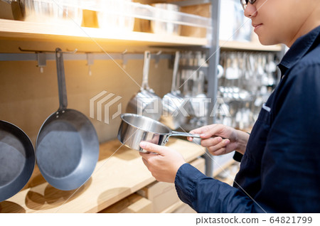 Asian man choosing saucepan in kitchenware store Asian man choosing saucepan in kitchenware store 64821799
