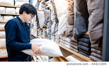 Asian man choosing throw pillow in furniture store Asian man choosing throw pillow in furniture store 64821809