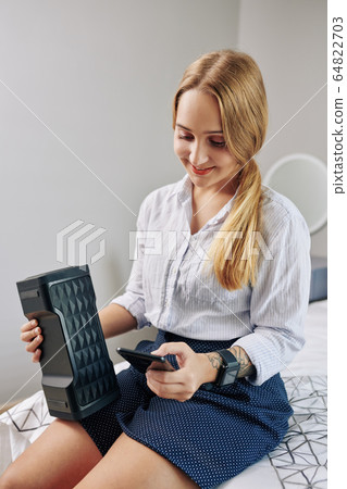 Woman adjusting speaker volume 64822703