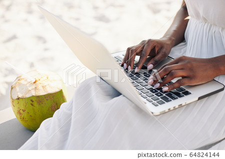 Woman working on laptop on beach Woman working on laptop on beach 64824144