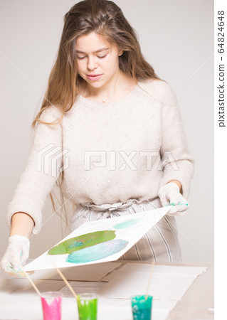 The girl creates a picture with abstraction in bright colors. 64824648