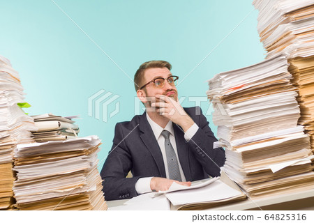 Shocked businessman sitting at the table with many Shocked businessman sitting at the table with many 64825316