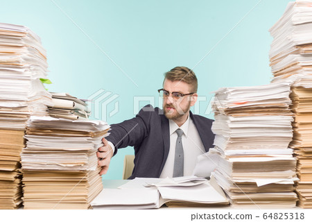 Shocked businessman sitting at the table with many Shocked businessman sitting at the table with many 64825318