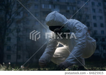 Scientist doing research outdoors, wearing white coverall and gas mask 64825915