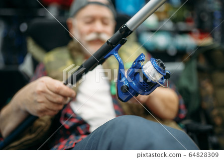 Angler with rod sitting in chair, fishing shop 64828309
