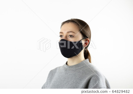 Portrait of young woman wearing black face mask isolated on gray background. Dust protection against virus. Coronavirus pandemic time. Female looking at camera 64829482