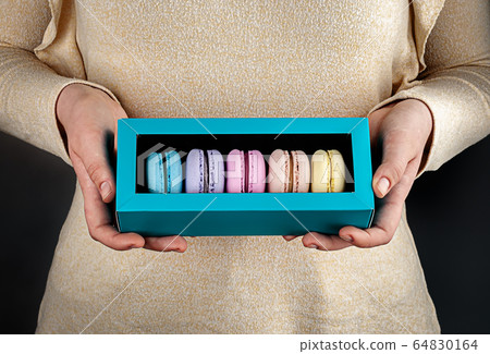 Girl hold one gift box with macaroons Girl hold one gift box with macaroons 64830164