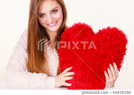 Happy woman holding heart shaped pillow Happy woman holding heart shaped pillow 64830290