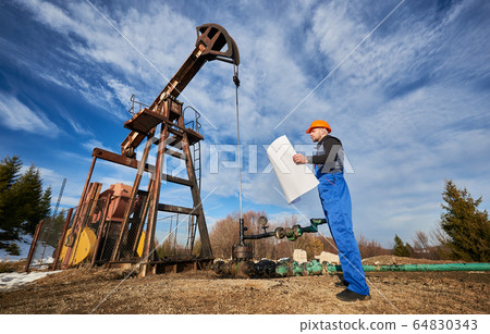 Oil man controlling work of pump jack. 64830343