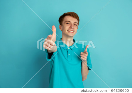 Caucasian young man's monochrome portrait on blue studio background, emotinal and beautiful Caucasian young man's monochrome portrait on blue studio background, emotinal and beautiful 64830600