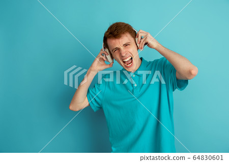 Caucasian young man's monochrome portrait on blue studio background, emotinal and beautiful Caucasian young man's monochrome portrait on blue studio background, emotinal and beautiful 64830601