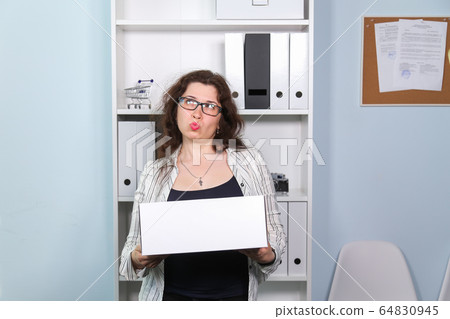 Concept of dismissal from work. Surprised woman with carton box with her stationery stuff, girl was fired from her job. Concept of dismissal from work. Surprised woman with carton box with her stationery stuff, girl was fired from her job. 64830945