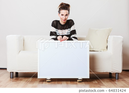 woman on sofa holding blank presentation board. woman on sofa holding blank presentation board. 64831424