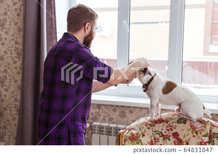 Happy young man sitting with his dog at home. Pet owner, animals and friendship concept. Happy young man sitting with his dog at home. Pet owner, animals and friendship concept. 64831847