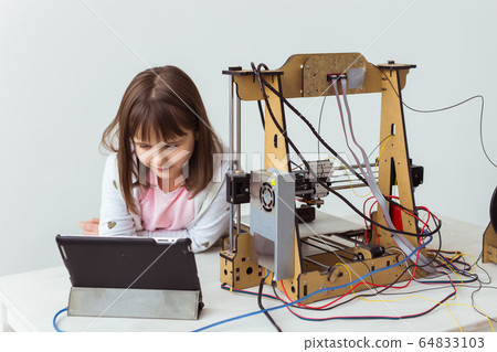 Cute girl with 3d printed shutter shades is watching her 3d printer as it prints her 3d model. Cute girl with 3d printed shutter shades is watching her 3d printer as it prints her 3d model. 64833103