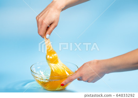 Depilation and beauty concept - sugar paste or honey wax for hair removing spatula with wooden framing sticks on a bright blue background 64833292