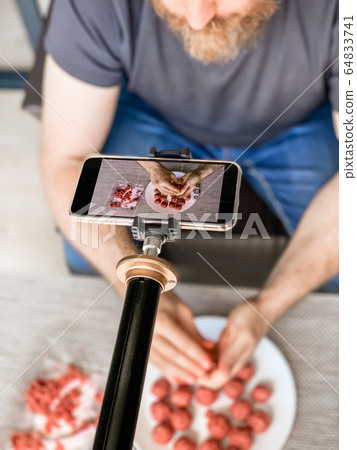 Man preparing meatballs recording video smartphone 64833741
