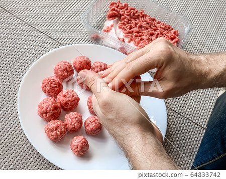 Man hands preparing meatballs with raw mincemeat Man hands preparing meatballs with raw mincemeat 64833742