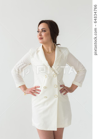 Girl in white suit with make-up posing on a white room. Fashion style body length studio portrait. Elegant fashionable woman. 64834766