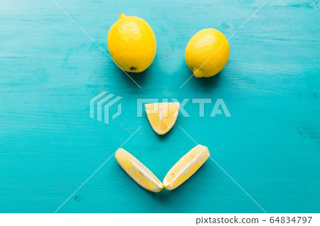 Smiling face made from half of ripe yellow fruit on blue background top view, happy diet, lemons and summer concept. Smiling face made from half of ripe yellow fruit on blue background top view, happy diet, lemons and summer concept. 64834797