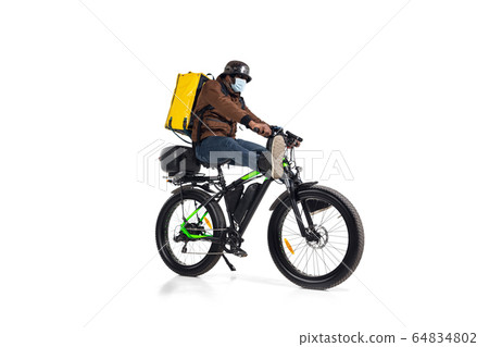 Too much orders. Contacless delivery service during quarantine. Man delivers food and shopping bags during isolation, wearing helmet and face mask. 64834802
