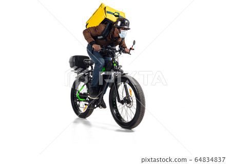 Too much orders. Contacless delivery service during quarantine. Man delivers food and shopping bags during isolation, wearing helmet and face mask. 64834837