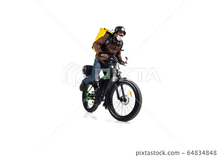 Too much orders. Contacless delivery service during quarantine. Man delivers food and shopping bags during isolation, wearing helmet and face mask. 64834848