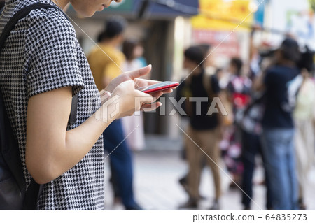 A young woman operating a smartphone hand A young woman operating a smartphone hand 64835273