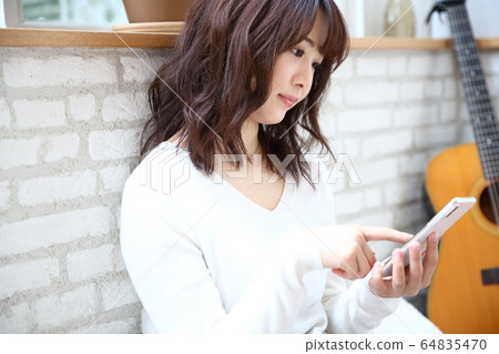 Image of woman operating smartphone at home Image of woman operating smartphone at home 64835470