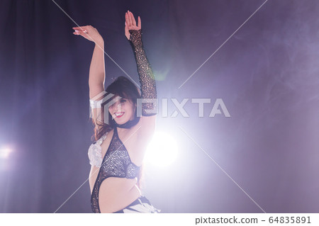Young woman belly dancer in exotic dress with gold, dancing tribal fusion dance in studio. Copy space. Young woman belly dancer in exotic dress with gold, dancing tribal fusion dance in studio. Copy space. 64835891