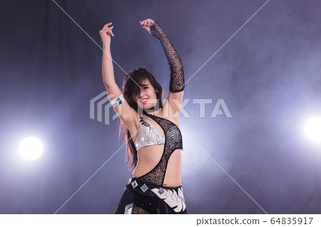 Young woman dancing in Tribal Fusion style. Belly dance on the stage. 64835917