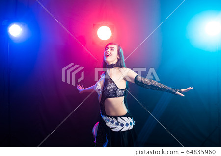 Young woman belly dancer in exotic dress with gold, dancing tribal fusion dance in studio. 64835960